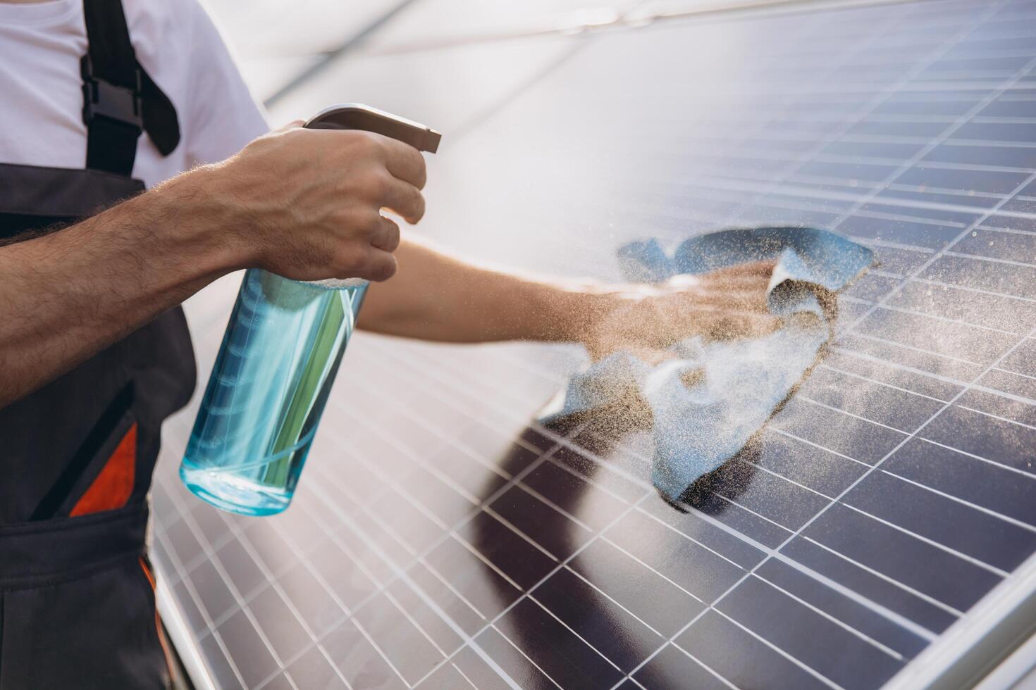 Close-up of a worker cleaning solar panels at a solar power plant or farm, spraying detergent, professional cleaning, solar panels. photo