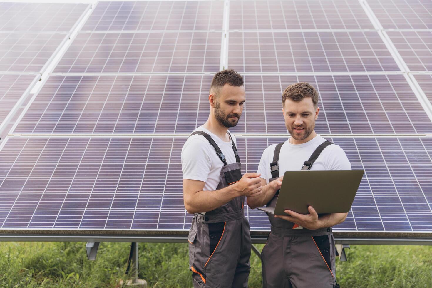 Energy specialist using digital tablet reading information to check the efficiency of solar panel construction. Green energy jobs. Technology. Two solar power plant workers are recording data photo