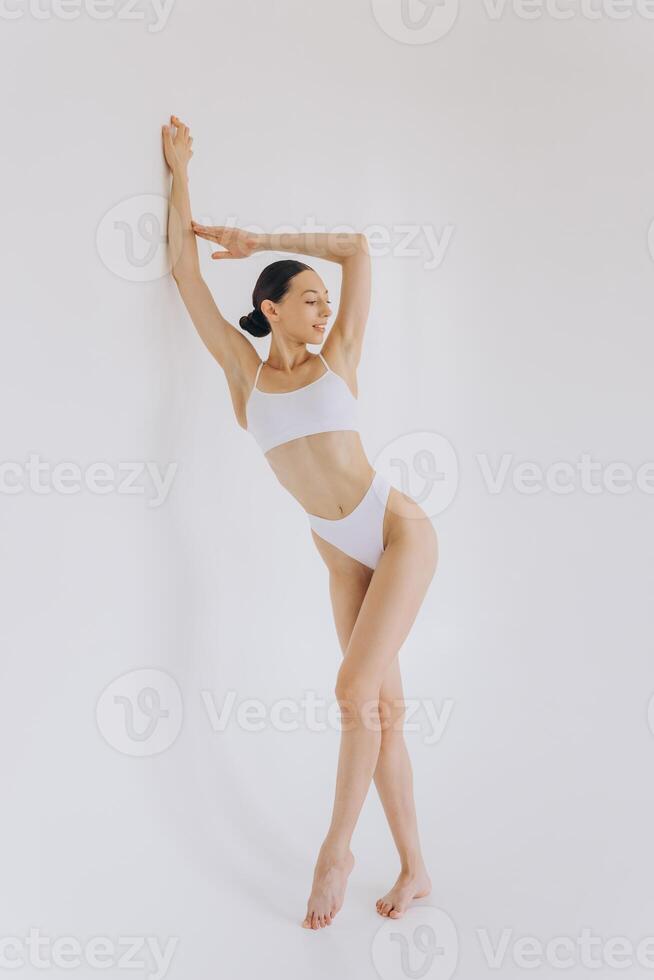 Full-length portrait of beautiful woman with slim body in underwear posing in the white studio background with copy space, mock-up photo