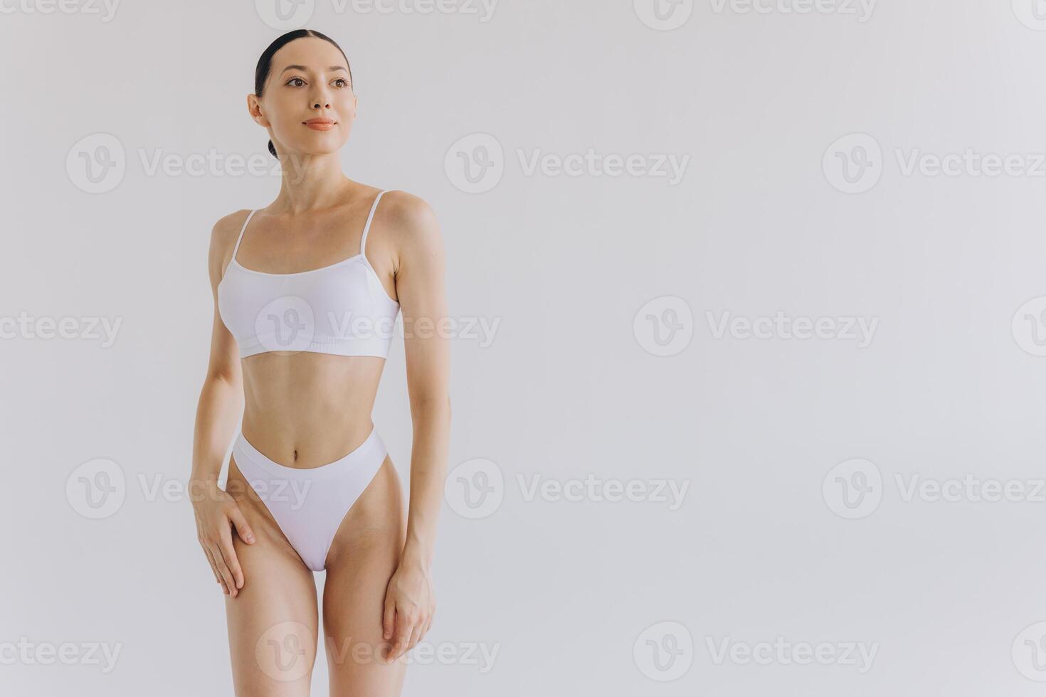 Portrait of beautiful woman with slim body in underwear posing in the white studio background with copy space, mock-up photo
