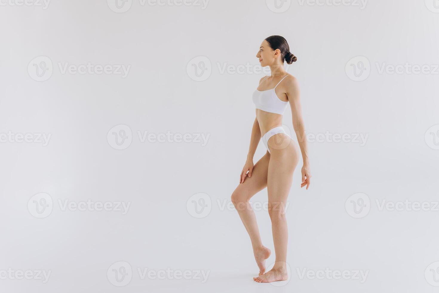 Full-length portrait of beautiful woman with slim body in underwear posing in the white studio background with copy space, mock-up photo