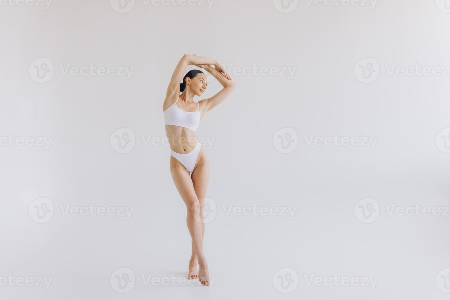 Full-length portrait of beautiful woman with slim body in underwear posing in the white studio background with copy space, mock-up photo