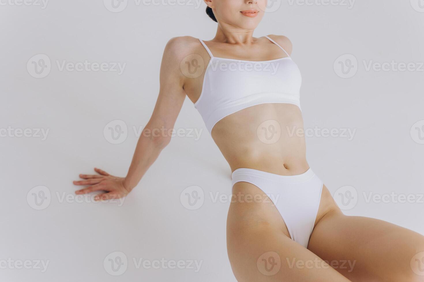 Close-up of Part of Ideal Female Body, Slim Woman in White Underwear Lying Down on Back, Happy Dreaming Girl Isolated over White Background with Copy Space, Mock-up. Beauty photo
