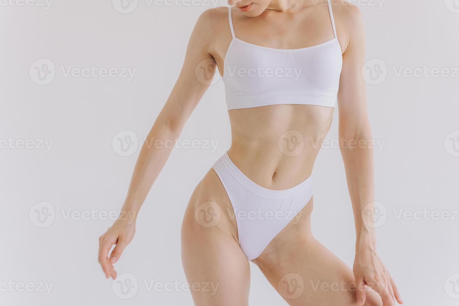 Close up view. Beautiful woman with slim body in underwear posing in the white studio background. photo