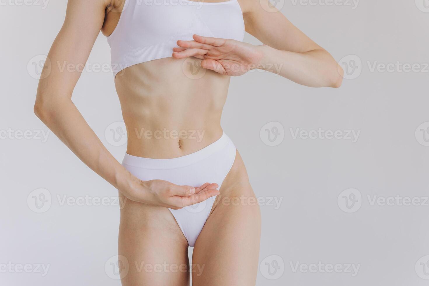 Close up shot of unrecognizable fit woman in lingerie isolated on white background. Torso of slim attractive female with flat belly in white underwear. Copy space for text. photo
