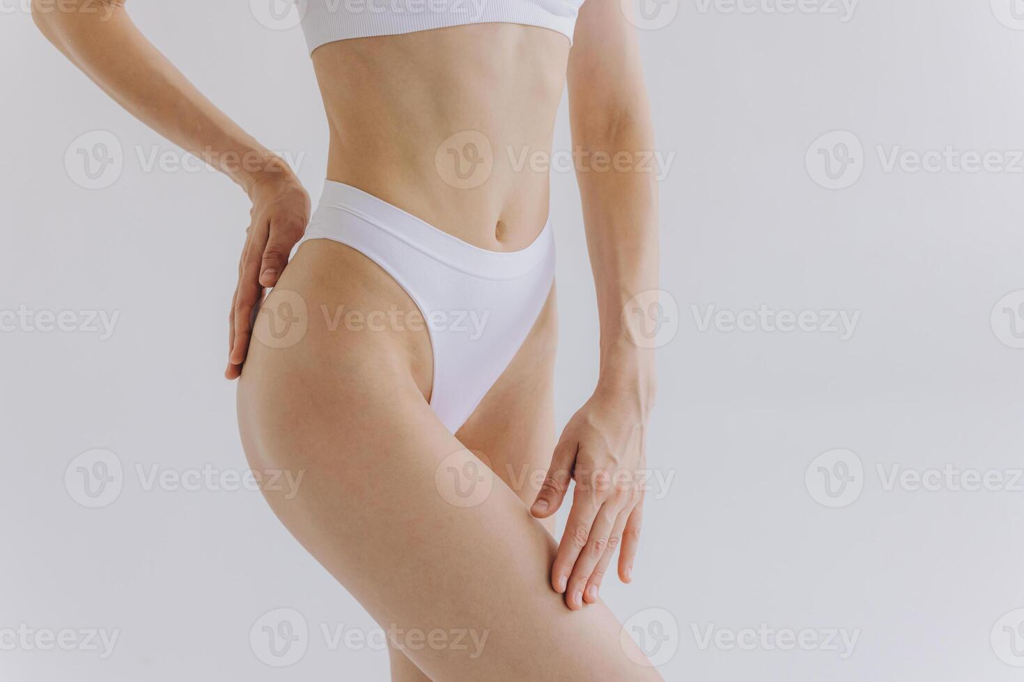 Close up shot of unrecognizable fit woman in lingerie isolated on white background. Torso of slim attractive female with flat belly in white underwear. Copy space for text. photo