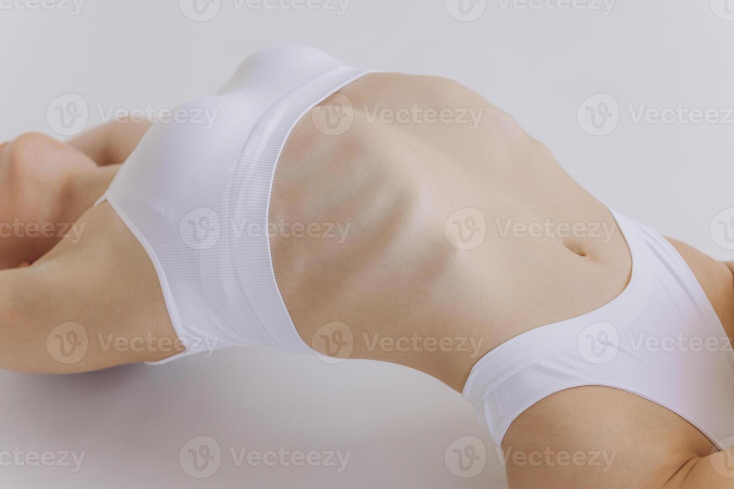 Close-up of Part of Ideal Female Body, Slim Woman in White Underwear Lying Down on Back, Happy Dreaming Girl Isolated over White Background with Copy Space, Mock-up. Beauty photo