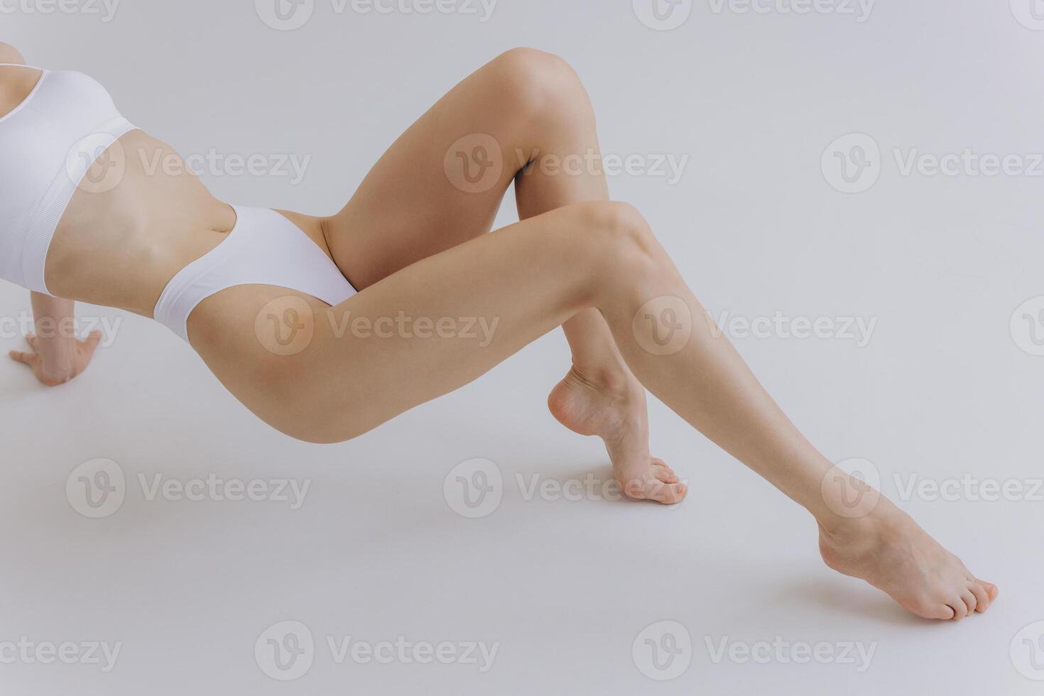 Close up part of perfect female body, legs and stomach, woman in white lingerie posing in white studio, mockup photo