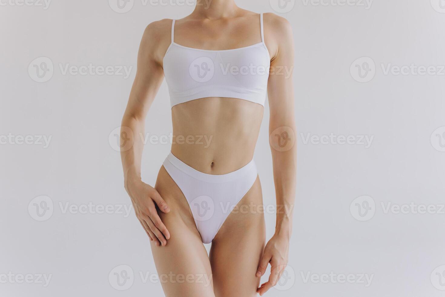 Close up shot of unrecognizable fit woman in lingerie isolated on white background. Torso of slim attractive female with flat belly in white underwear. Copy space for text. photo