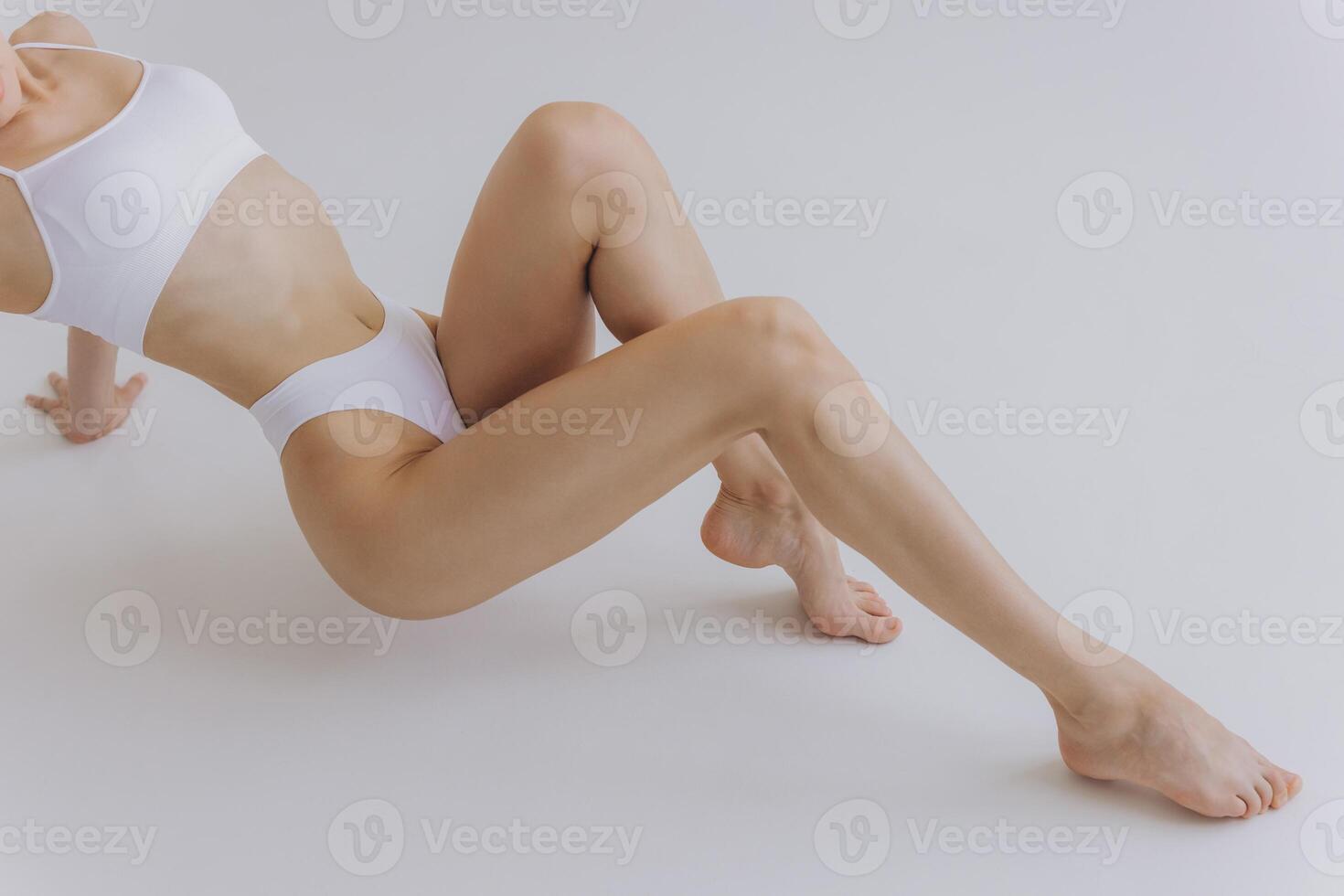 Close up part of perfect female body, legs and stomach, woman in white lingerie posing in white studio, mockup photo