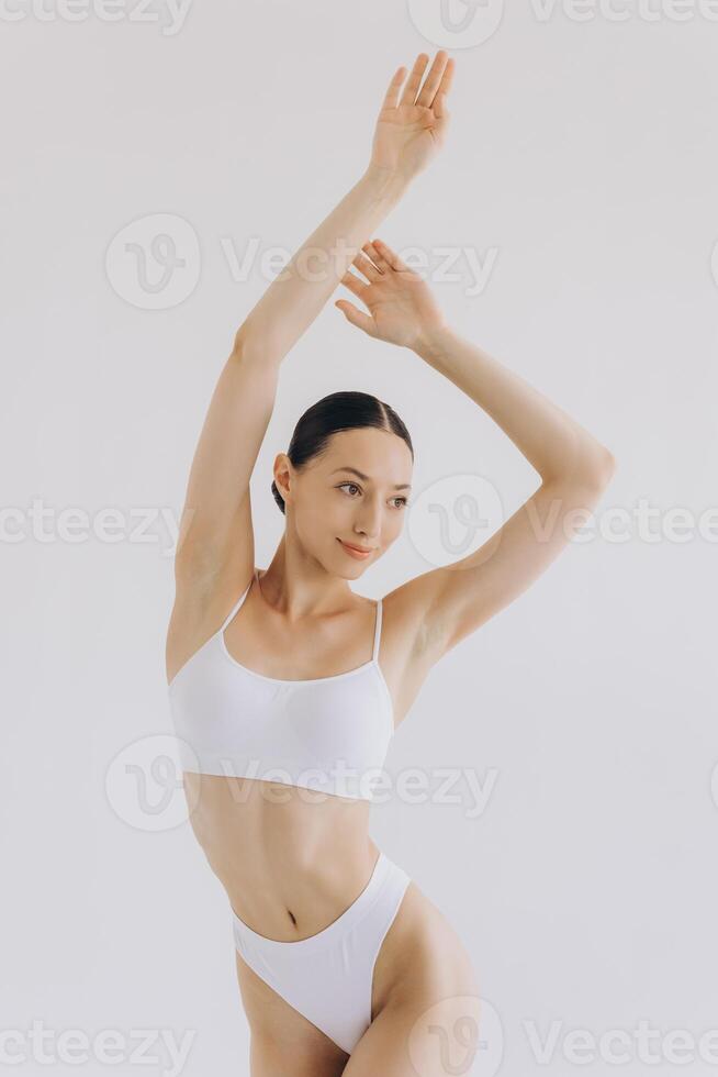 Image of sensual, beautiful young woman with slim body shape posing in elegant white lingerie isolated on white background. photo