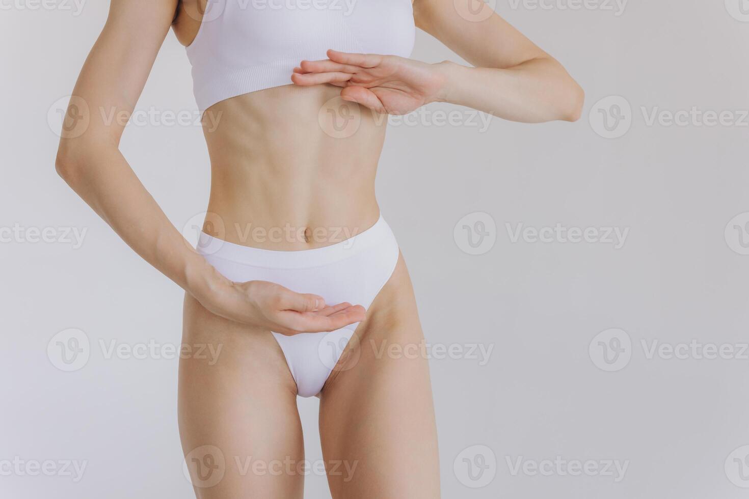Close up shot of unrecognizable fit woman in lingerie isolated on white background. Torso of slim attractive female with flat belly in white underwear. Copy space for text. photo