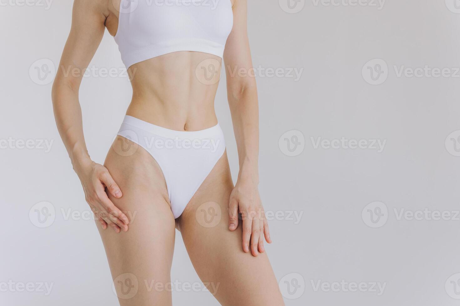 Close up shot of unrecognizable fit woman in lingerie isolated on white background. Torso of slim attractive female with flat belly in white underwear. Copy space for text. photo