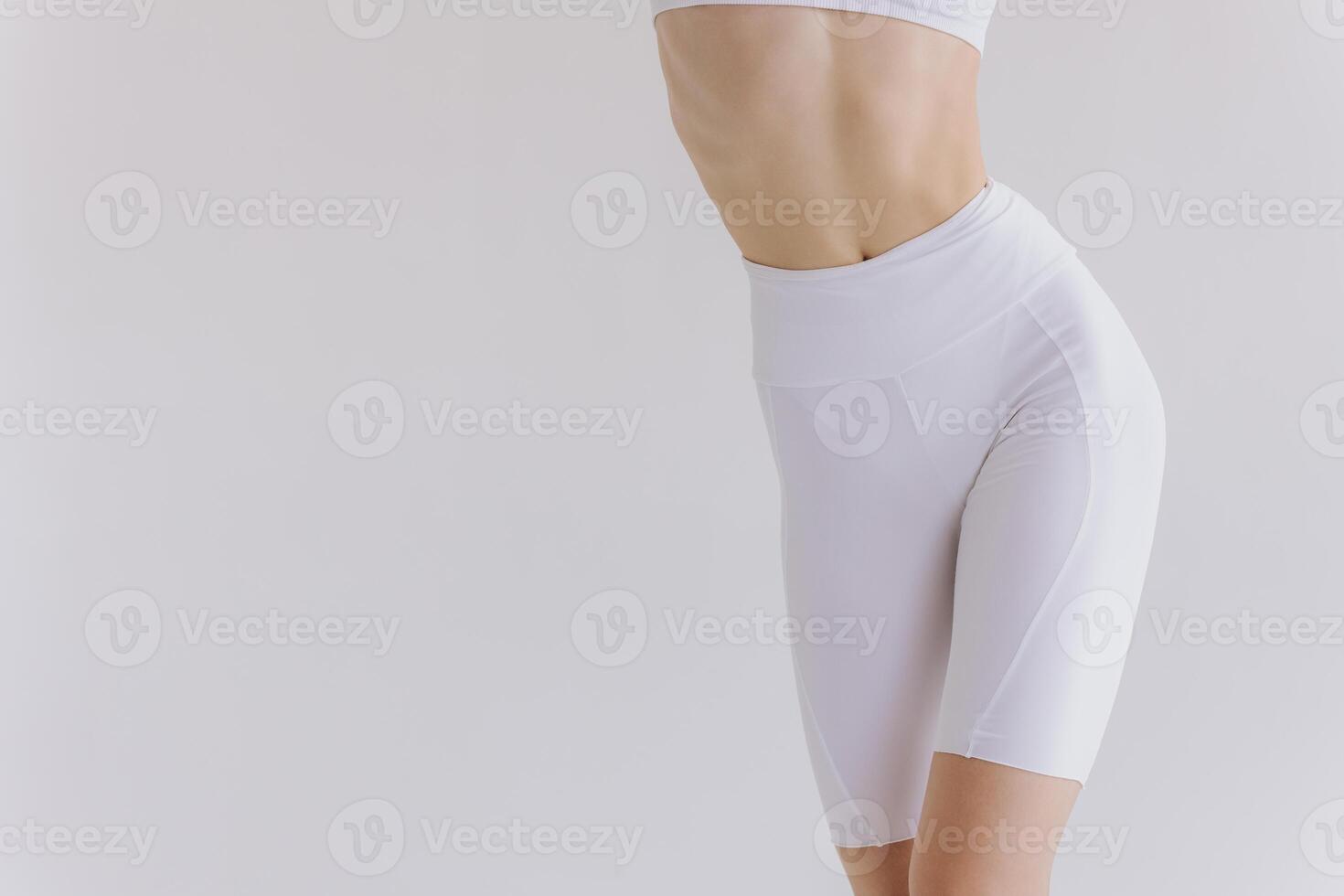 Close-up woman showing perfect body and sports stomach. Healthy fitness and eating lifestyle concept. Fitness sporty woman showing well trained body, abs muscles, isolated over white background photo