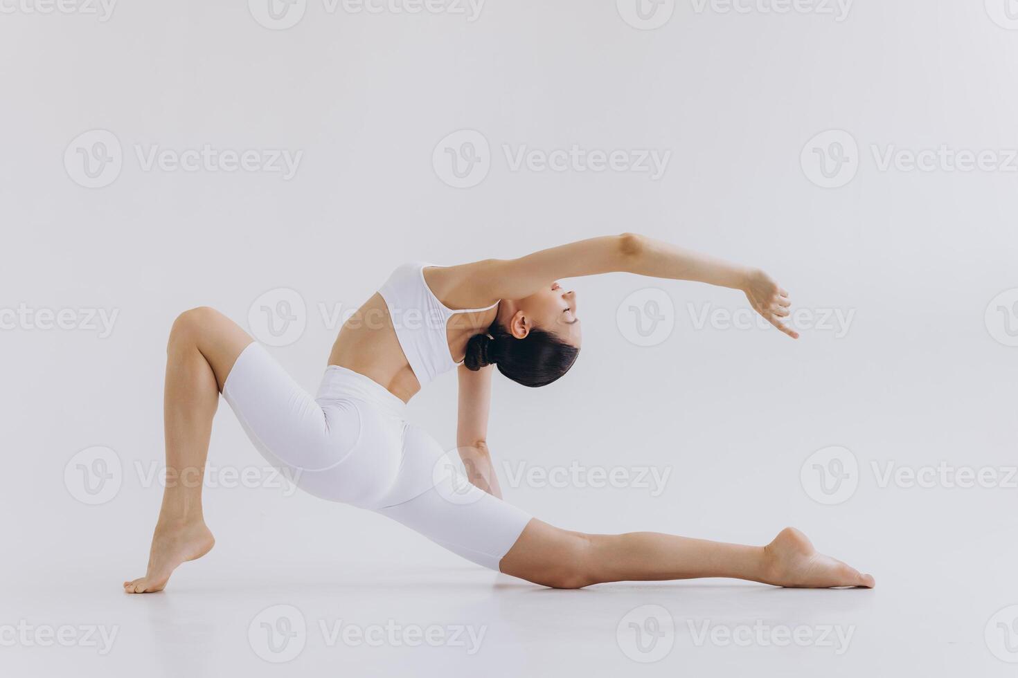 Full length image of sporty young woman with slim body doing yoga practice isolated on white background - concept of healthy life and natural balance between body and mental development photo