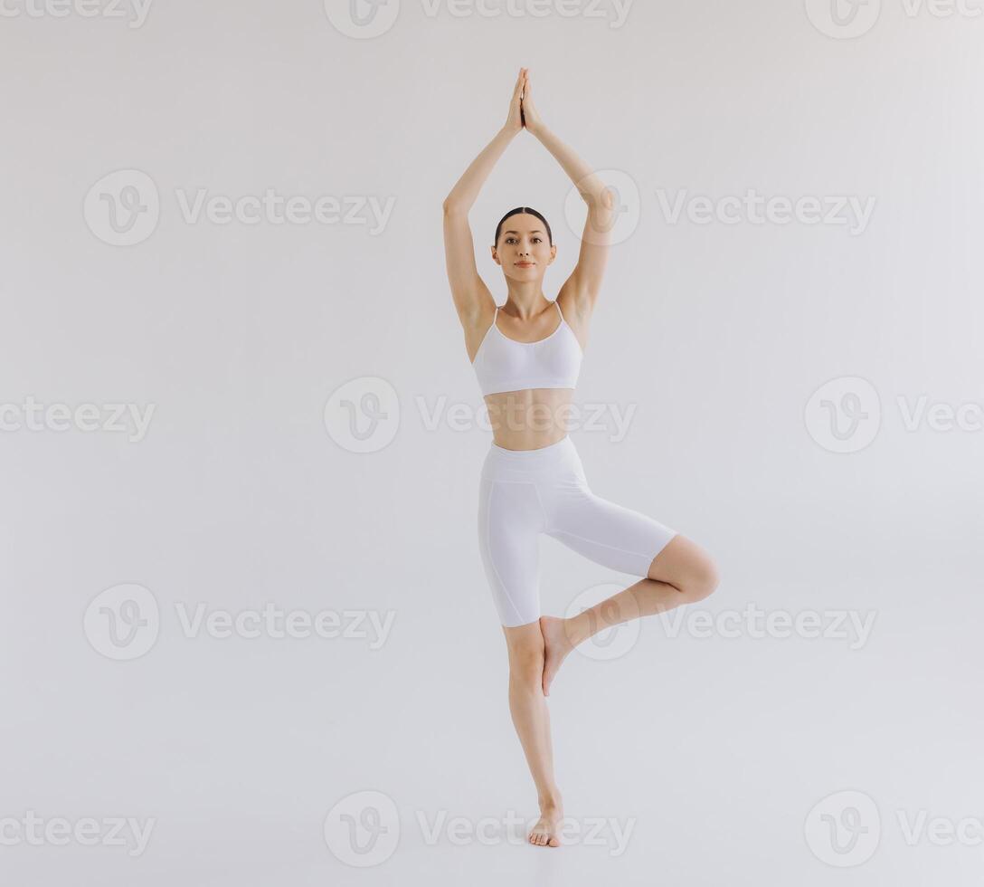 Full length of sporty young woman with slim body doing yoga practice isolated on white background - concept of healthy life and natural balance between body and mental development photo
