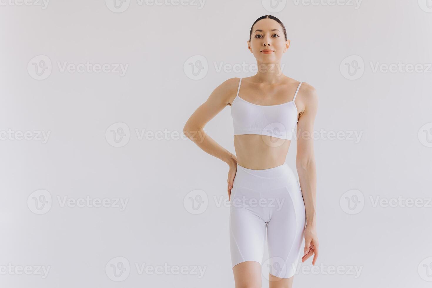 Young slim woman in white sportwear on white background isolated. Muscular slim attractive female with flat belly. Copy space for text. Body care, healthy and sporty life, hair removal, yoga concept photo