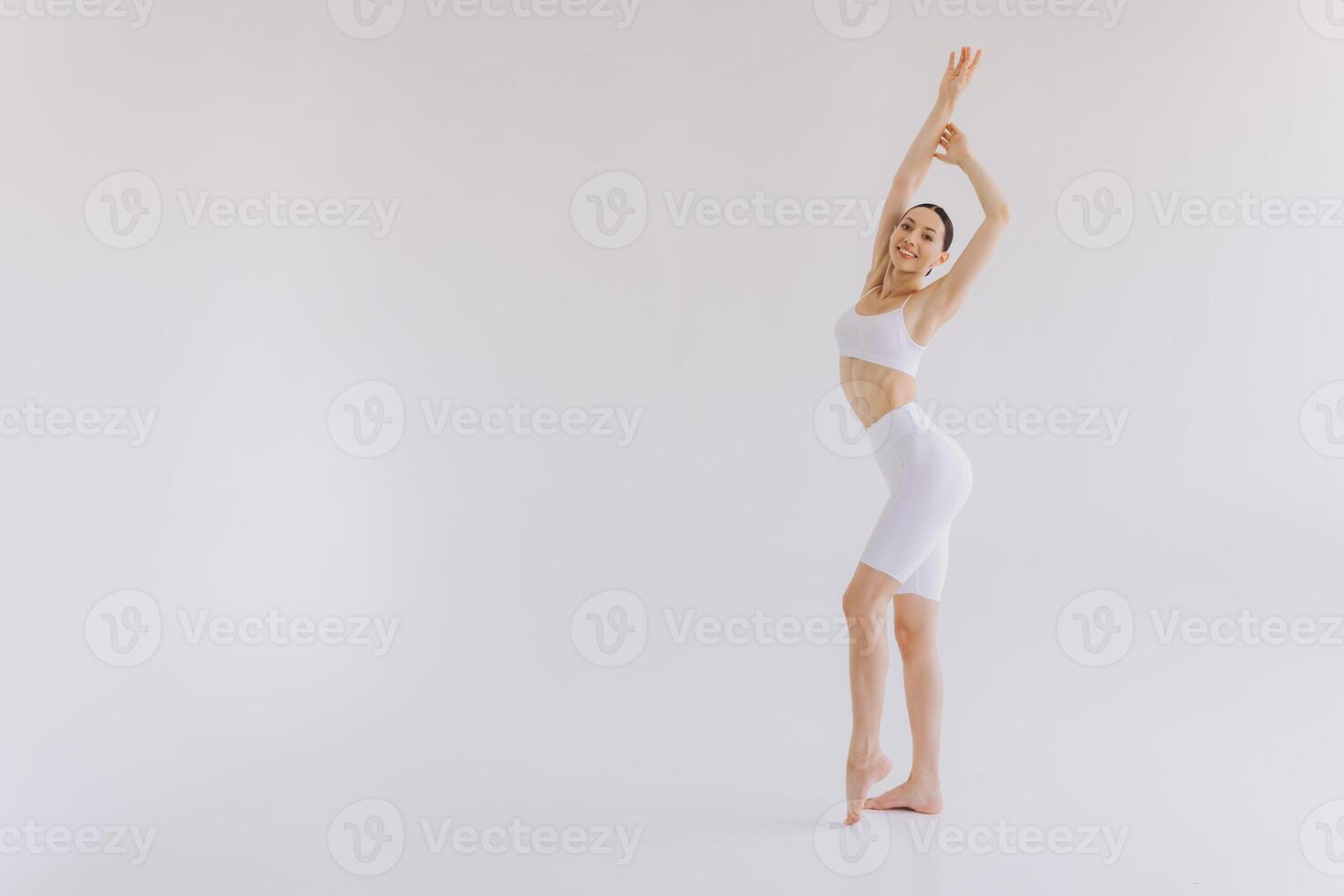 Slim woman in white sportwear on white background isolated. Muscular slim attractive female with flat belly. Copy space for text. Body care, healthy and sporty life, hair removal, yoga concept photo