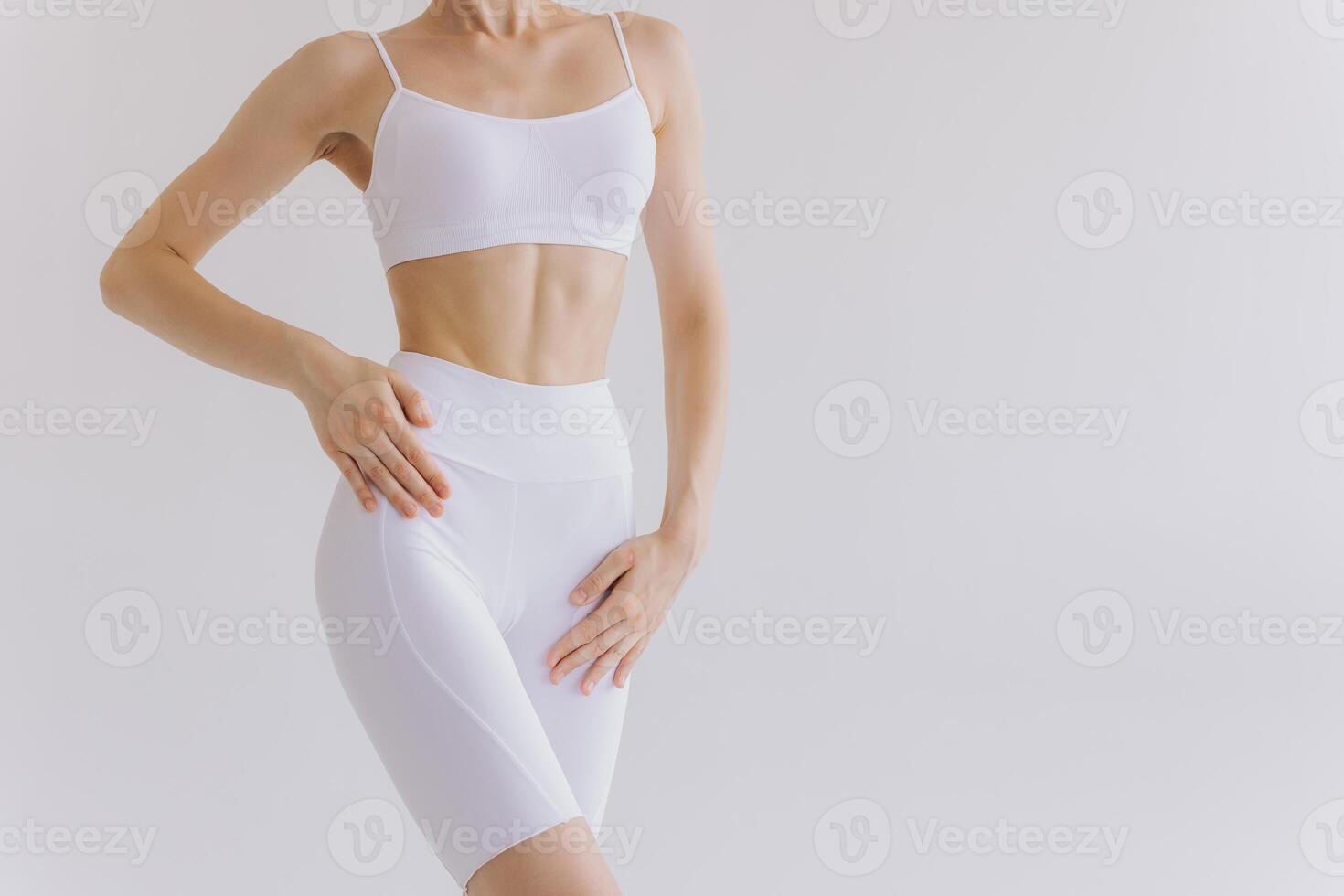 Close-up woman showing perfect body and sports stomach. Healthy fitness and eating lifestyle concept. Fitness sporty woman showing well trained body, abs muscles, isolated over white background photo
