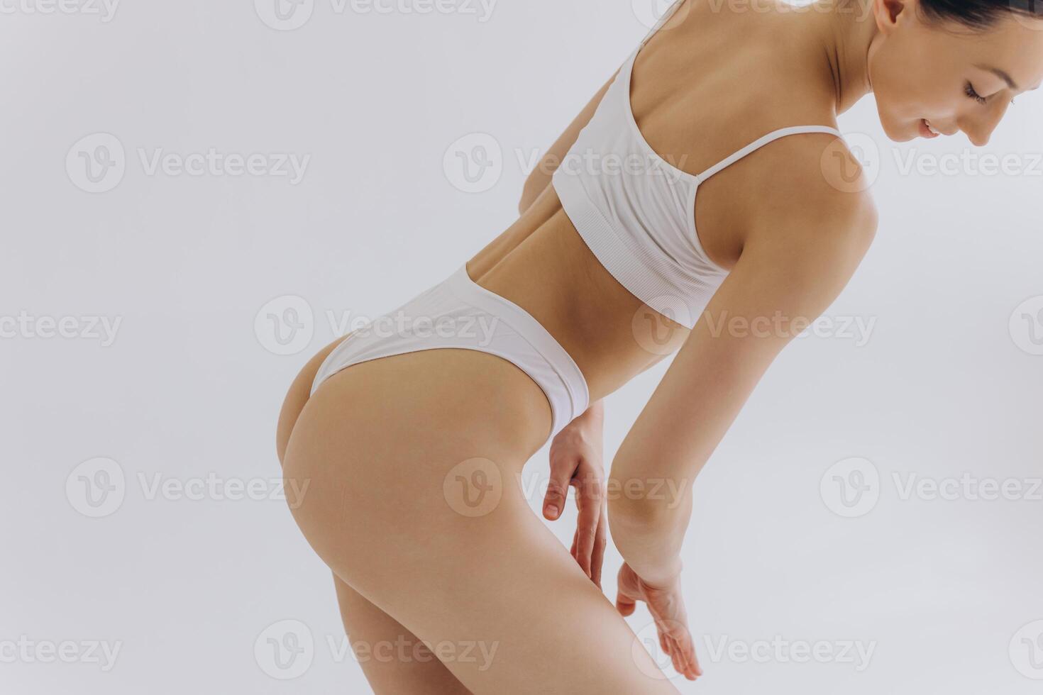 Close up view. Crop image of woman with slim body and perfect stomach in underwear posing in the white studio background. photo