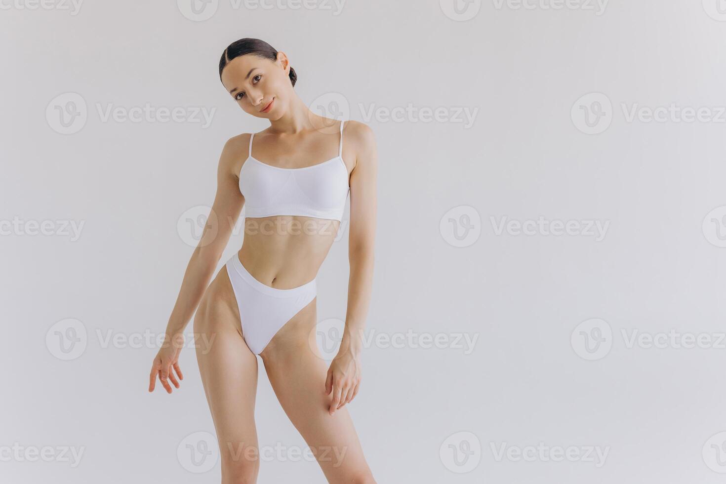 Close up view. Beautiful woman with slim body and perfect stomach in underwear posing in white studio background. photo