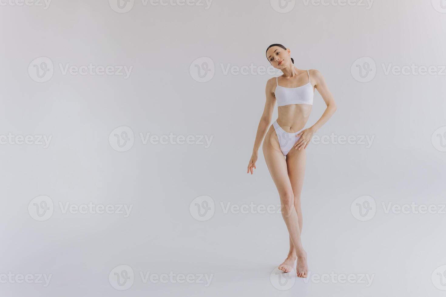 Full-length portrait of beautiful woman with slim body in underwear posing in the white studio background with copy space, mock-up photo