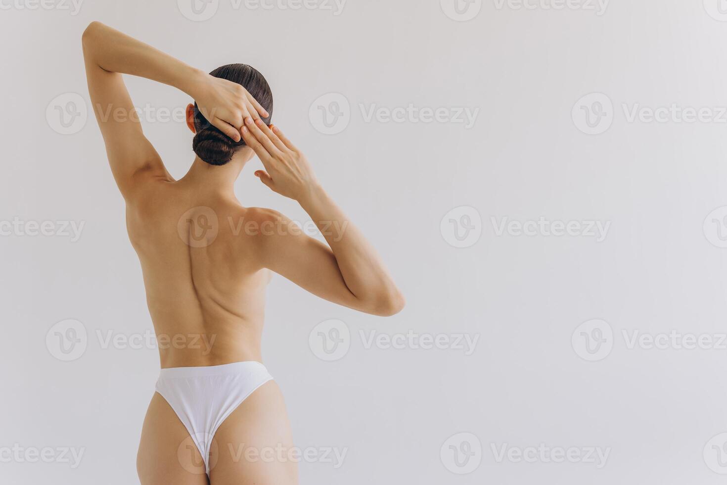 Cropped back rear view young sexy lady woman with slim body perfect skin wearing nude top bra lingerie stand hold hands on thighs isolated on white background. Lifestyle diet fit concept photo