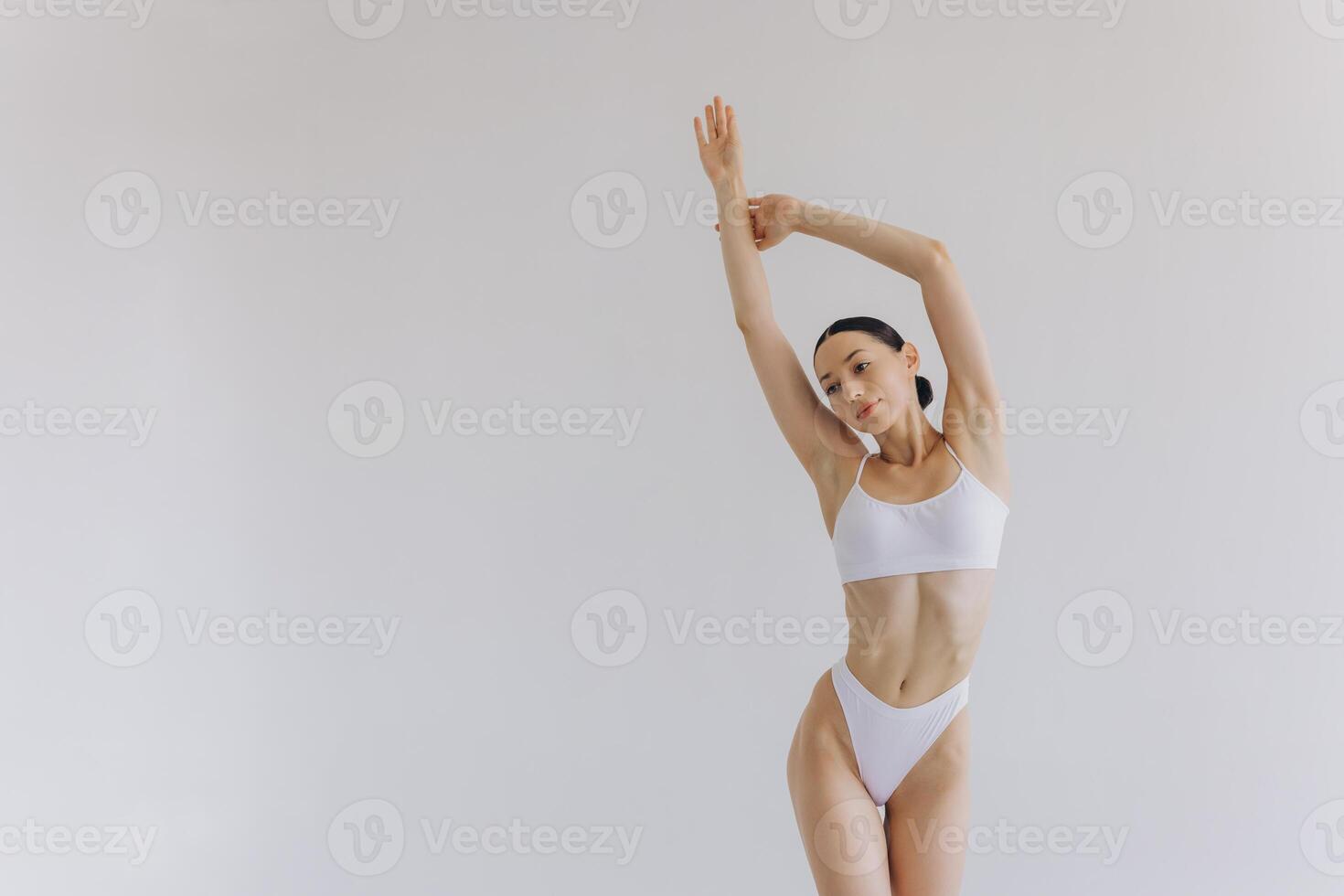 Beautiful woman with slim body and perfect stomach in white underwear posing in white studio background. photo
