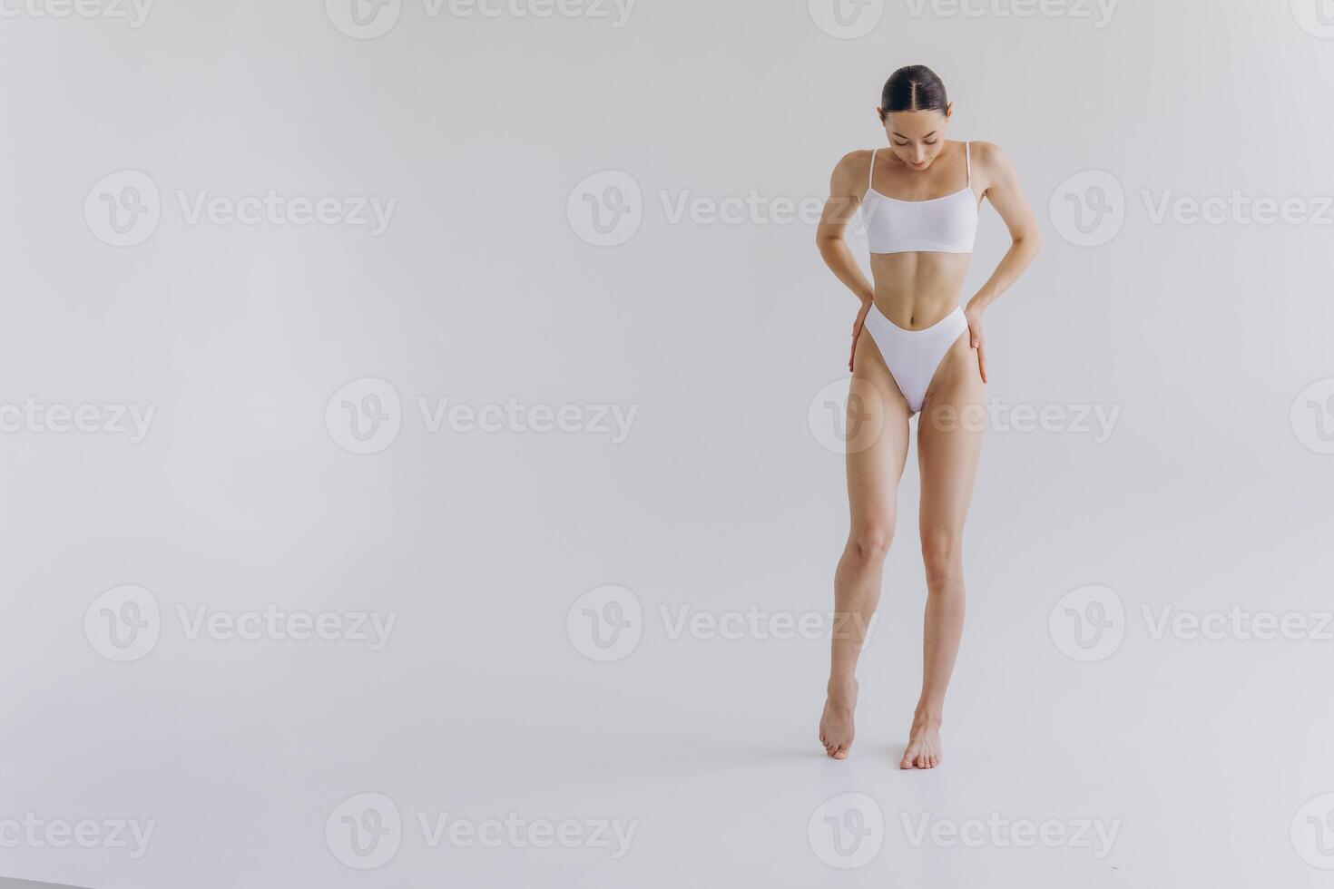 Full-length portrait of beautiful woman with slim body in underwear posing in the white studio background with copy space, mock-up photo