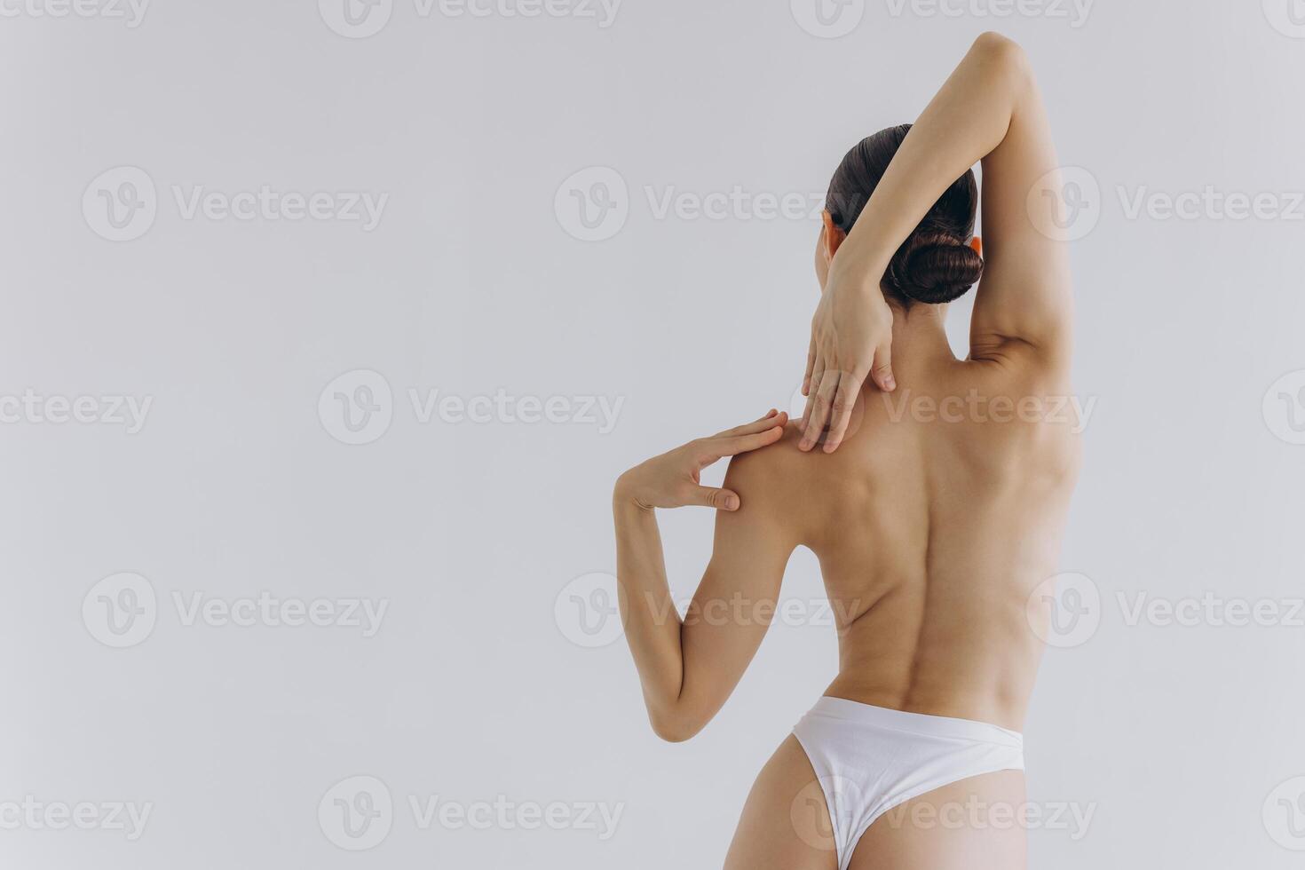 Cropped back rear view young sexy lady woman with slim body perfect skin wearing nude top bra lingerie stand hold hands on thighs isolated on white background. Lifestyle diet fit concept photo