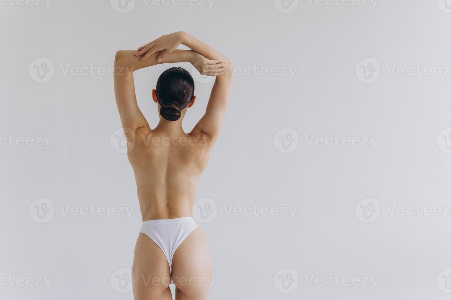 Cropped back rear view young sexy lady woman with slim body perfect skin wearing nude top bra lingerie stand hold hands on thighs isolated on white background. Lifestyle diet fit concept photo