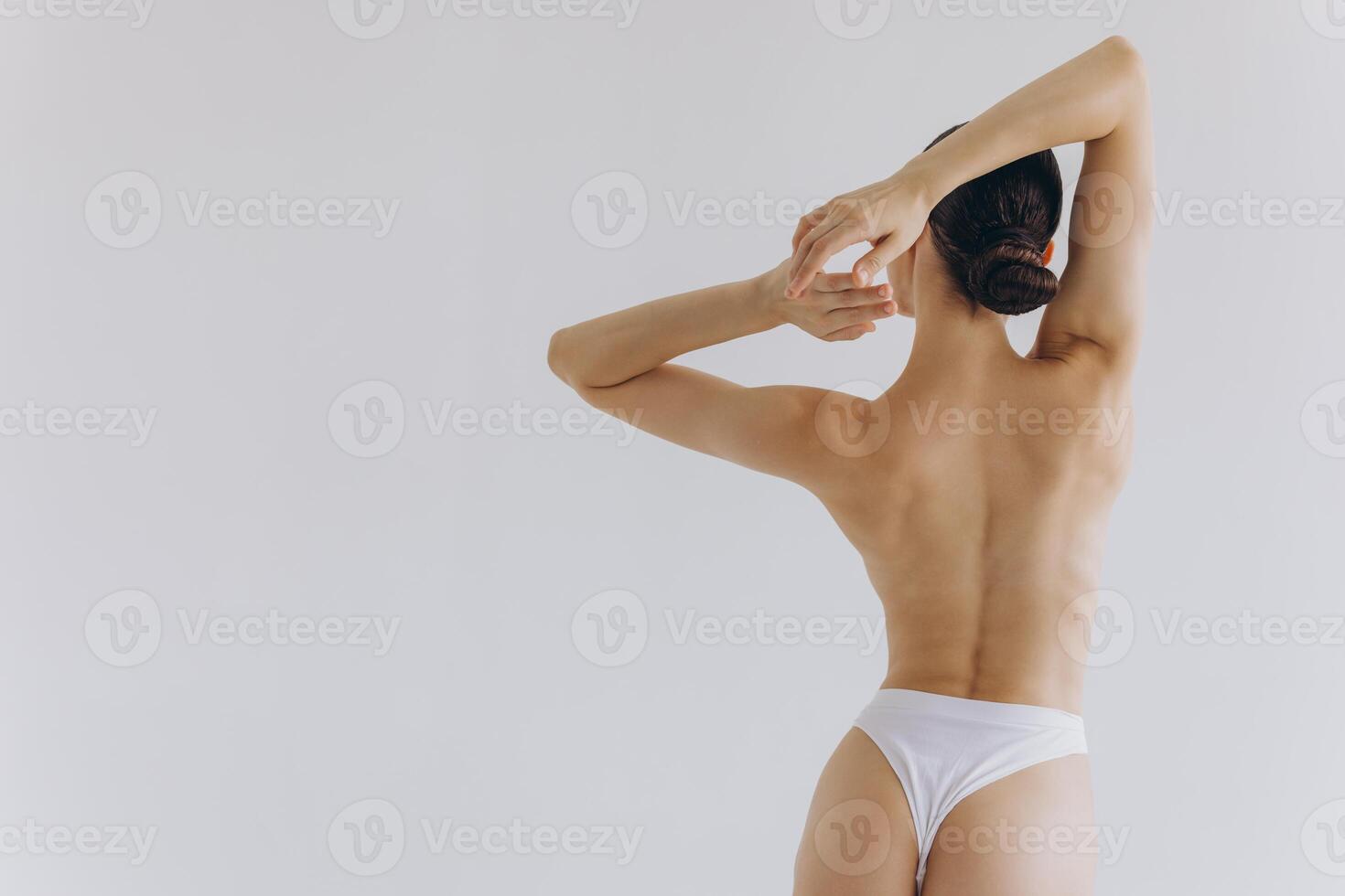Cropped back rear view young sexy lady woman with slim body perfect skin wearing nude top bra lingerie stand hold hands on thighs isolated on white background. Lifestyle diet fit concept photo