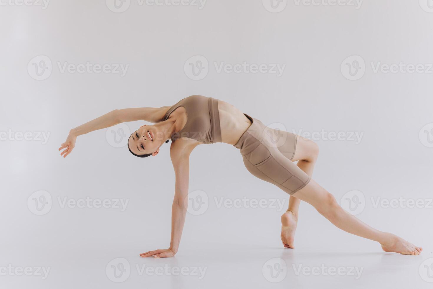 Sporty young woman with slim body doing yoga practice and stretching isolated on white background - concept of healthy life and natural balance between body and mental development photo