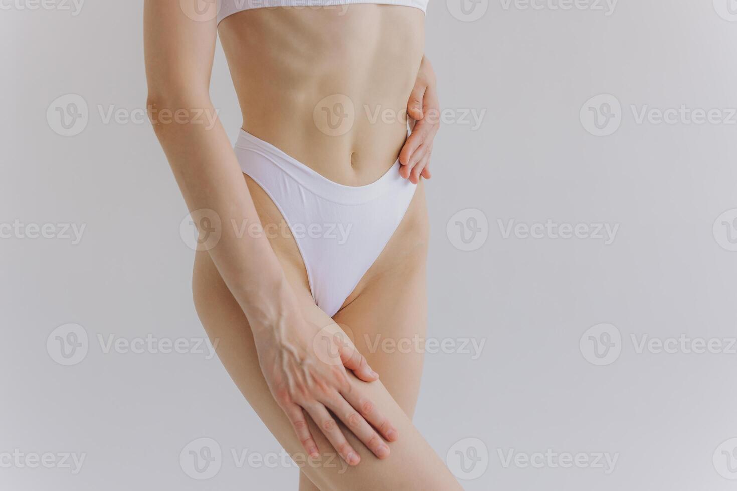 Close up view. Crop image of woman with slim body and perfect stomach in underwear posing in the white studio background. photo