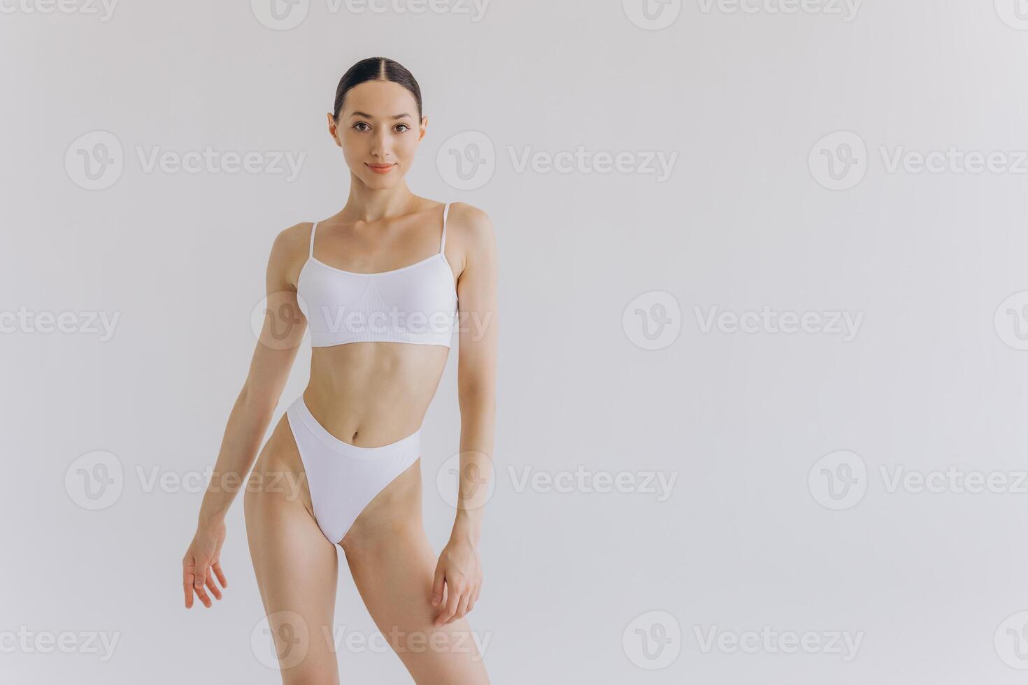 Close up view. Beautiful woman with slim body and perfect stomach in underwear posing in white studio background. photo