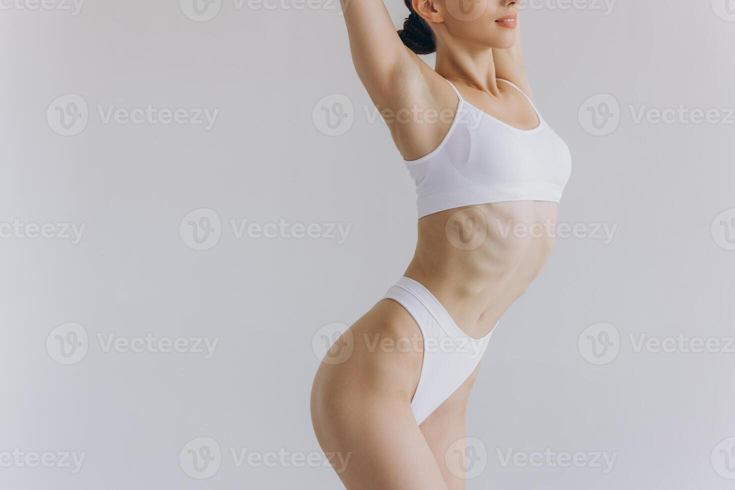 Close up view. Crop image of woman with slim body and perfect stomach in underwear posing in the white studio background. photo