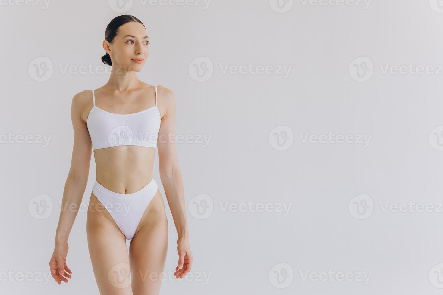 Portrait of beautiful woman with slim body in underwear posing in the white studio background with copy space, mock-up photo