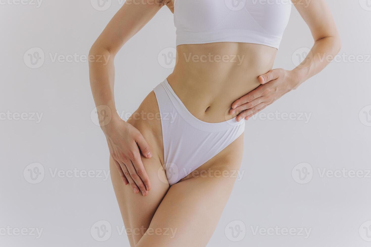 Close up view. Crop image of woman with slim body and perfect stomach in underwear posing in the white studio background. photo