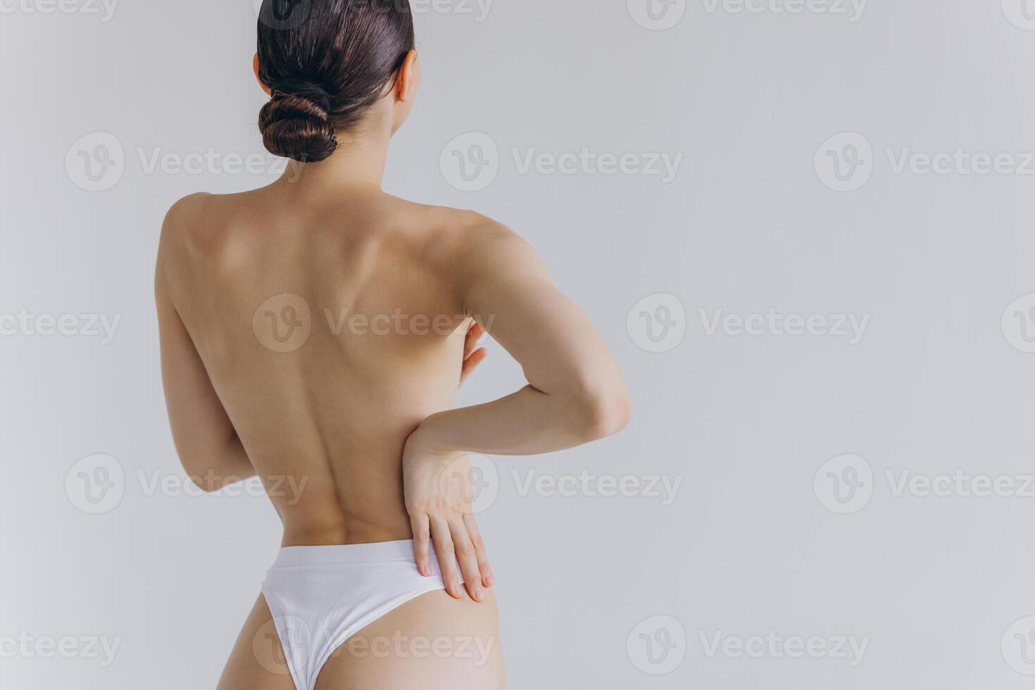 Cropped back rear view young sexy lady woman with slim body perfect skin wearing nude top bra lingerie stand hold hands on thighs isolated on white background. Lifestyle diet fit concept photo