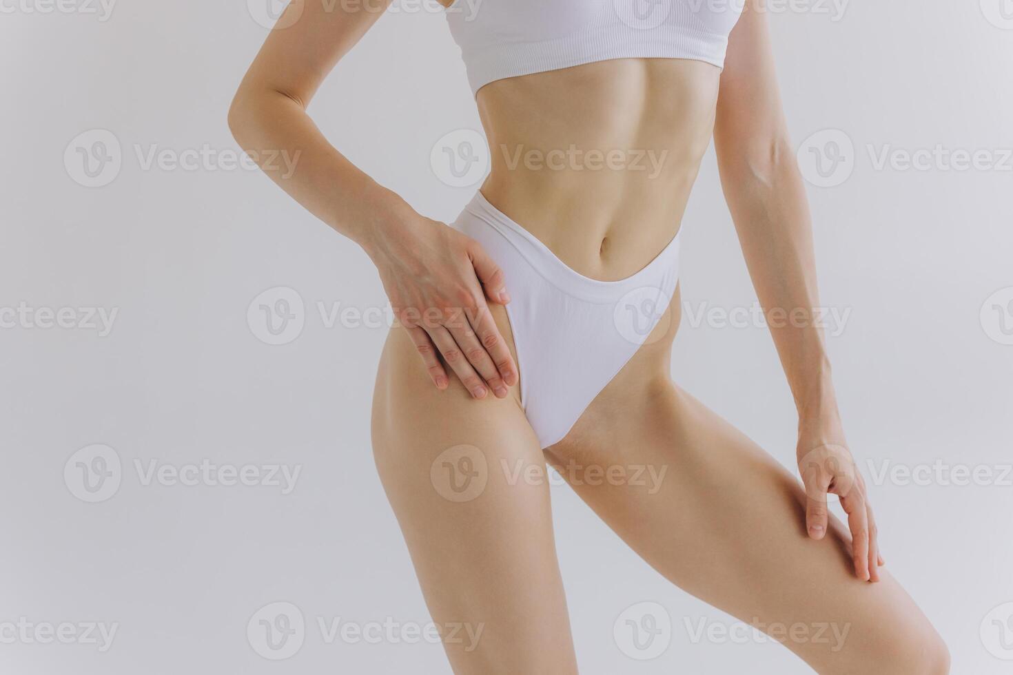 Close up view. Crop image of woman with slim body and perfect stomach in underwear posing in the white studio background. photo