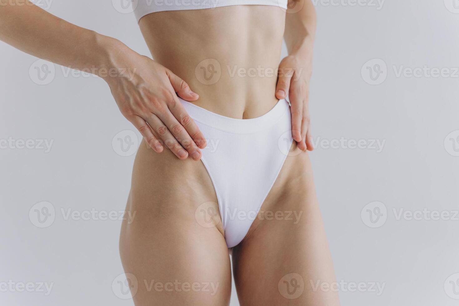 Close up view. Crop image of woman with slim body and perfect stomach in underwear posing in the white studio background. photo