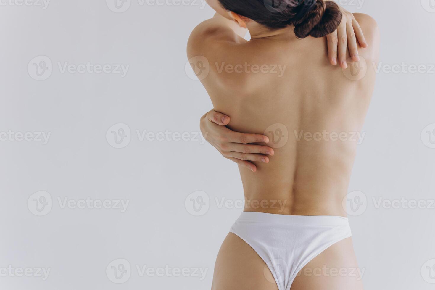 Cropped back rear view young sexy lady woman with slim body perfect skin wearing nude top bra lingerie stand hold hands on thighs isolated on white background. Lifestyle diet fit concept photo