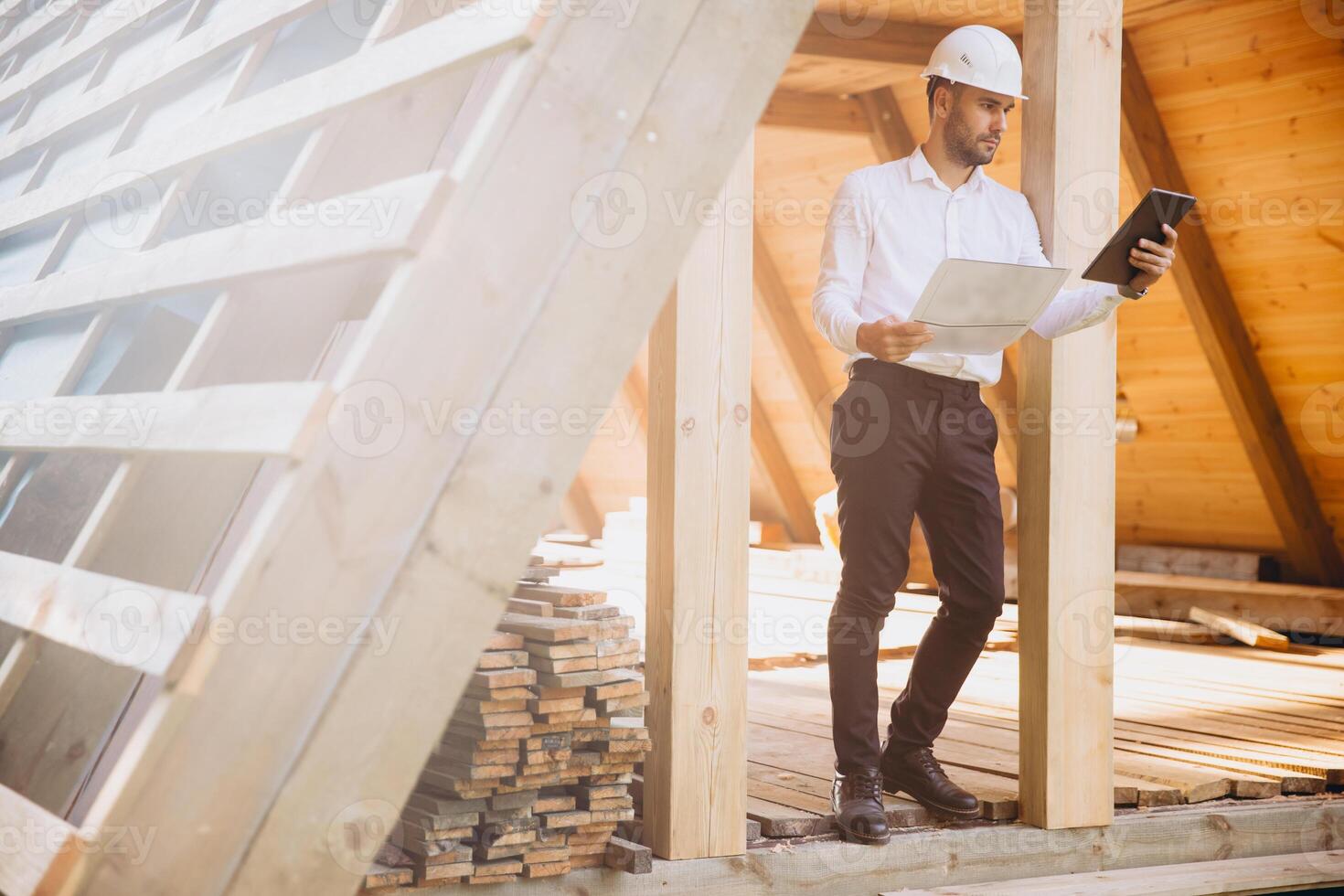 Foreman studies blueprints with tablet. Contractor for construction company. Architect in unfinished building. Builder in wooden house under construction. Man engineer from construction team photo