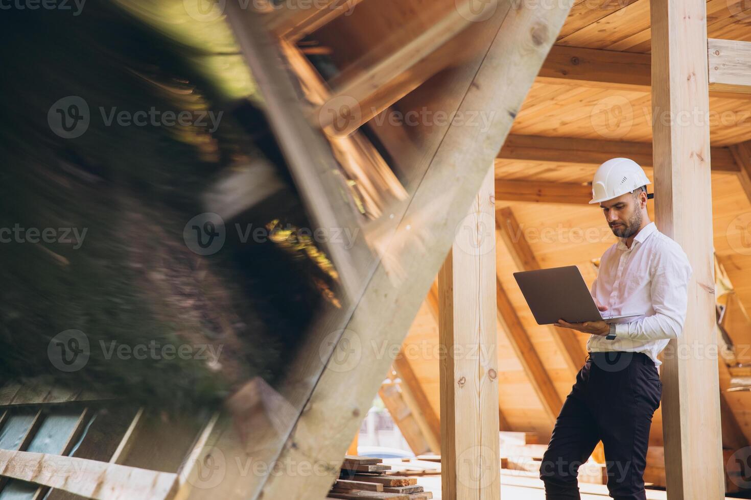 Man builder. Foreman with laptop. Contractor for construction company. Architect in unfinished building. Builder in wooden house under construction. Man engineer from construction team photo