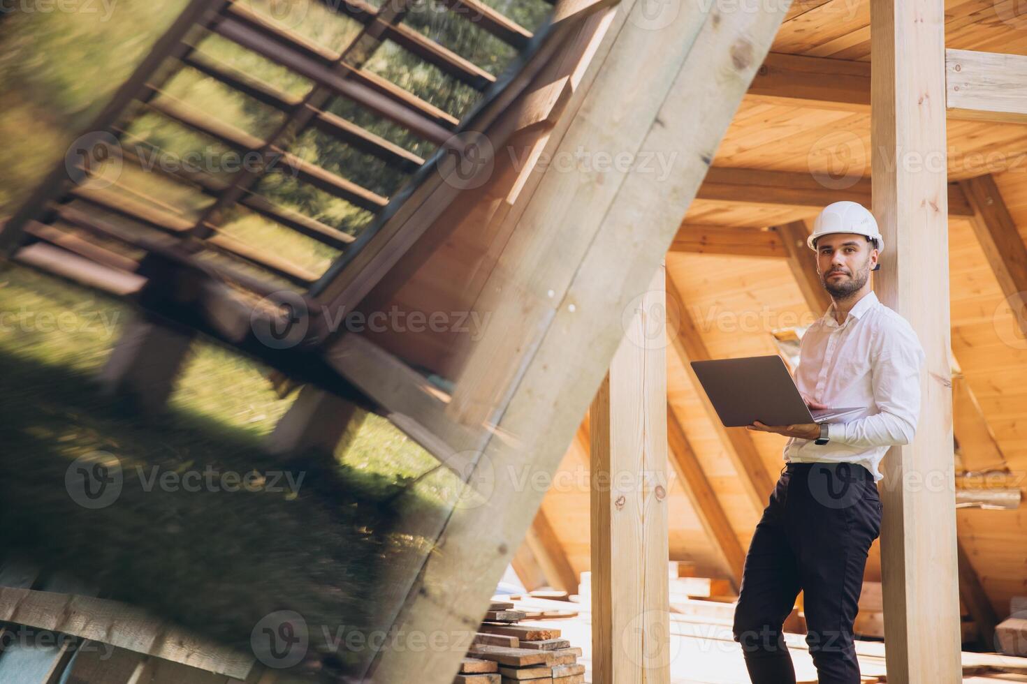 Man builder. Foreman with laptop. Contractor for construction company. Architect in unfinished building. Builder in wooden house under construction. Man engineer from construction team photo