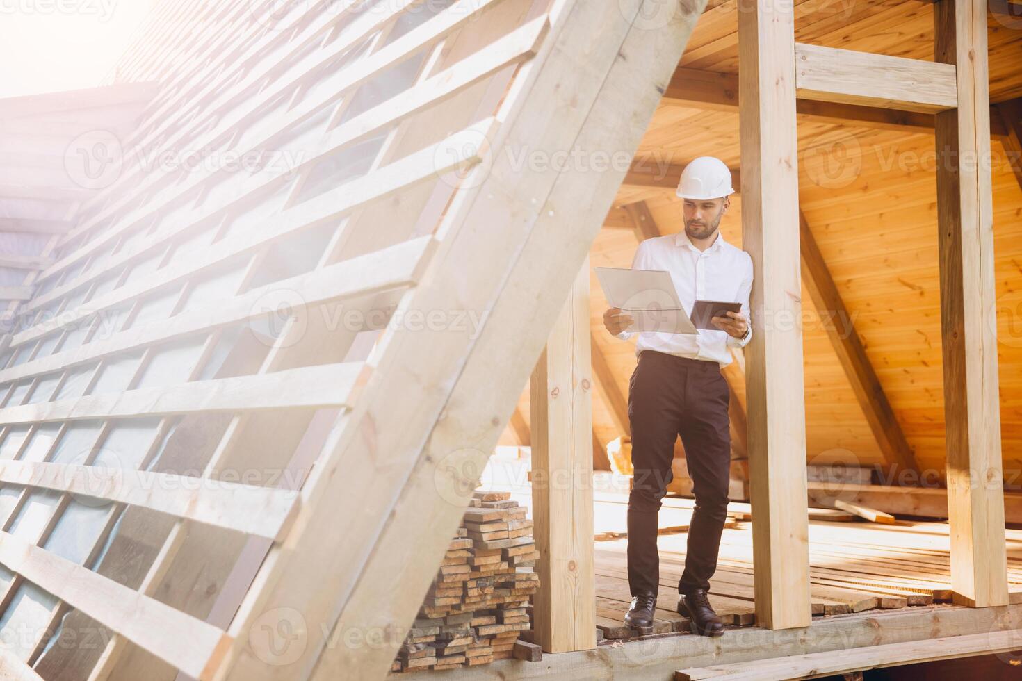 Foreman studies blueprints with tablet. Contractor for construction company. Architect in unfinished building. Builder in wooden house under construction. Man engineer from construction team photo