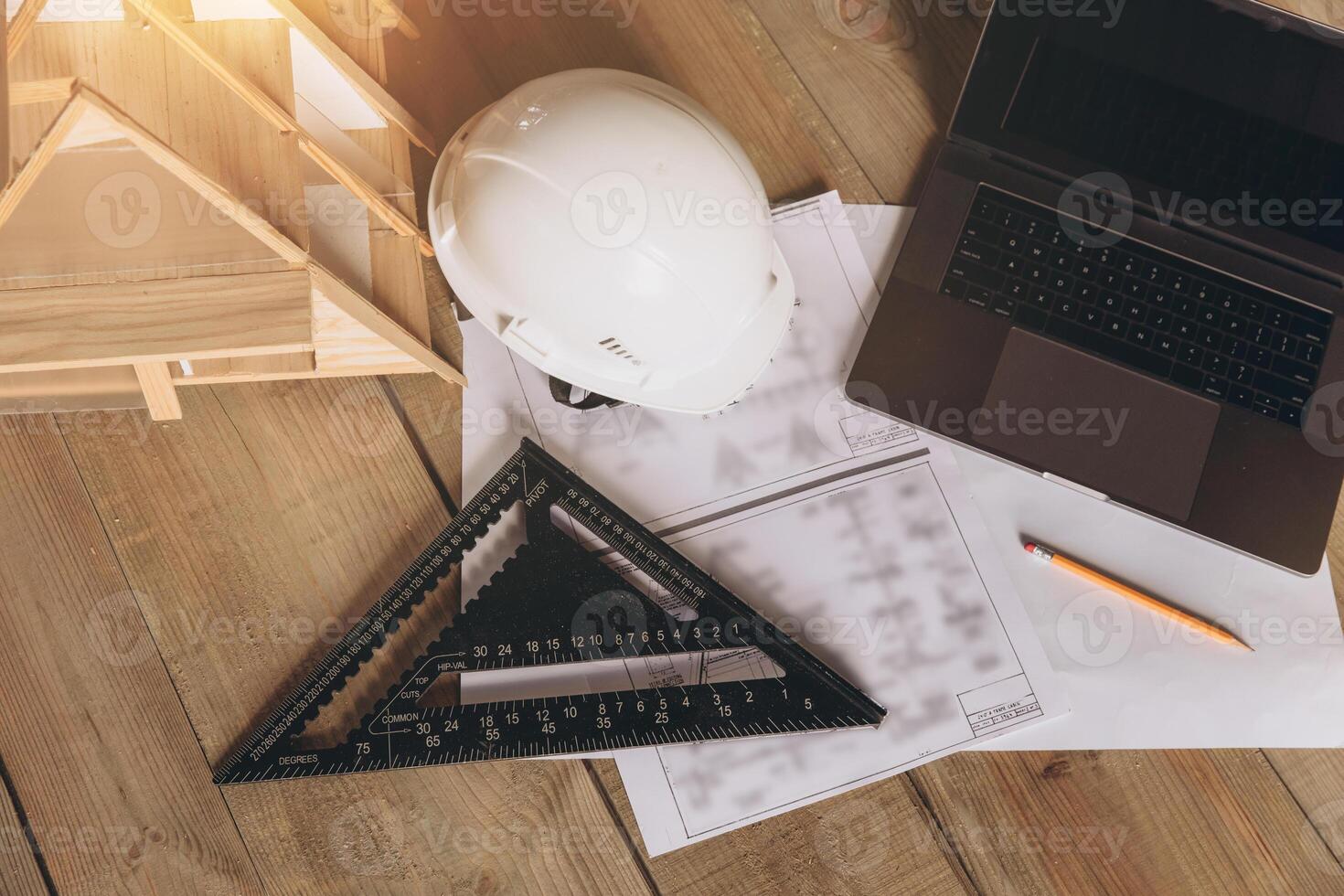 Top view mock -up architectural office desk with copy space, wooden floor with laptop, miniature model of house, white helmet construction, pencil, ruler and paper roll, copy space, mock up photo