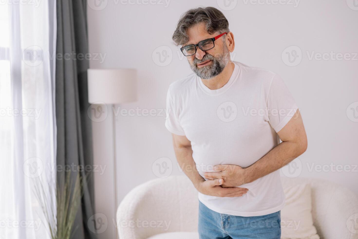 Elderly man suffering from digestive problems, liver and gall bladder problems and intestinal pain at home photo