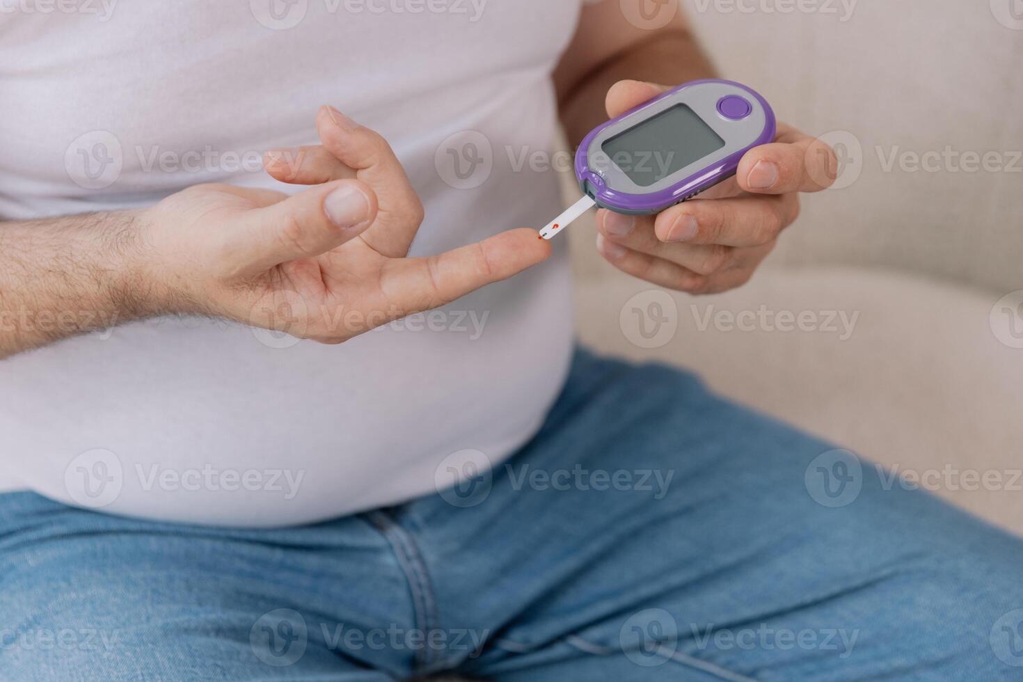 Diabetic senior man on wheelchair checking blood sugar level with fingerstick testing glucose meter. Elderly man with type 1 diabetes using blood glucose monitor at home. photo