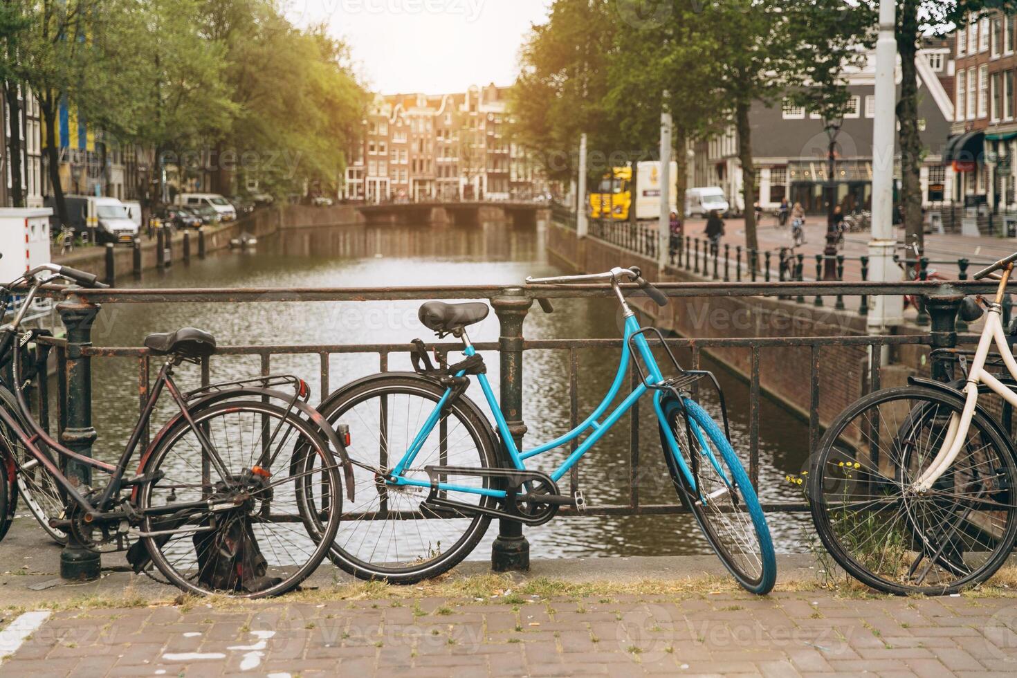 Old bicycle on the bridge in Amsterdam, Netherlands against a canal during summer sunny day. Postcard iconic view. Tourism concept. photo